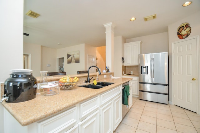 kitchen with sink, decorative columns, an island with sink, white cabinets, and appliances with stainless steel finishes