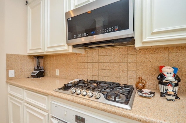 kitchen with tasteful backsplash, white cabinetry, and stainless steel appliances