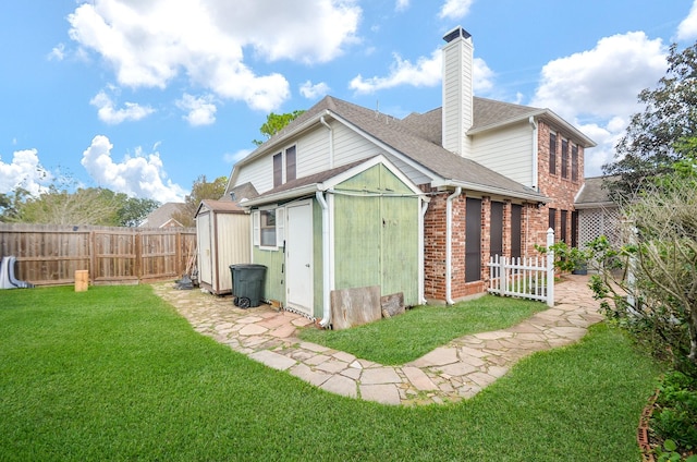 back of house with a lawn and a shed