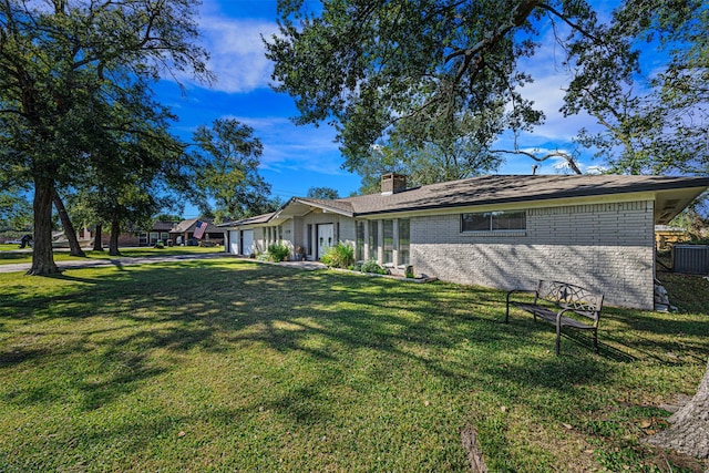 view of front facade with central AC unit, a garage, and a front lawn