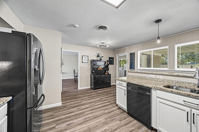 kitchen with stainless steel refrigerator, white cabinetry, dishwasher, and a wealth of natural light