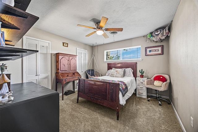 bedroom featuring carpet flooring, ceiling fan, a textured ceiling, and two closets