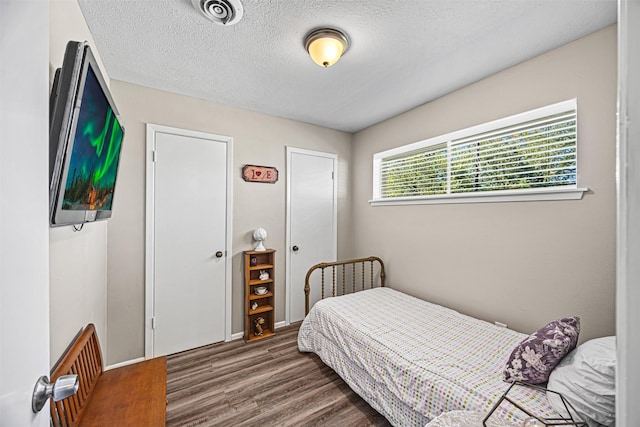 bedroom featuring a textured ceiling and dark hardwood / wood-style floors