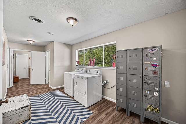 clothes washing area with a textured ceiling, washer and dryer, and dark hardwood / wood-style floors