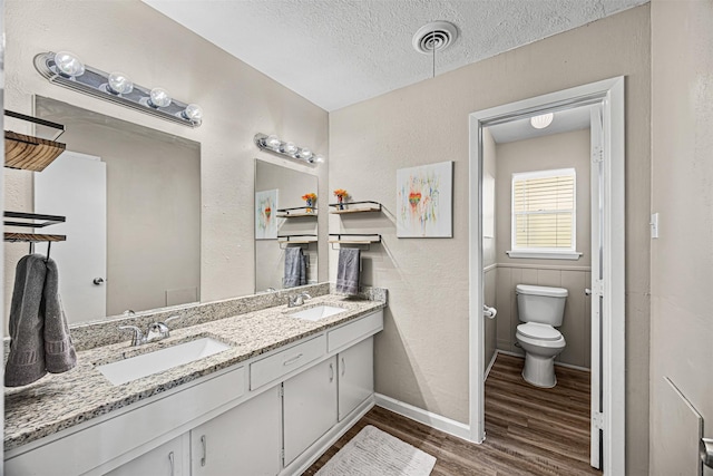 bathroom with hardwood / wood-style flooring, vanity, toilet, and a textured ceiling