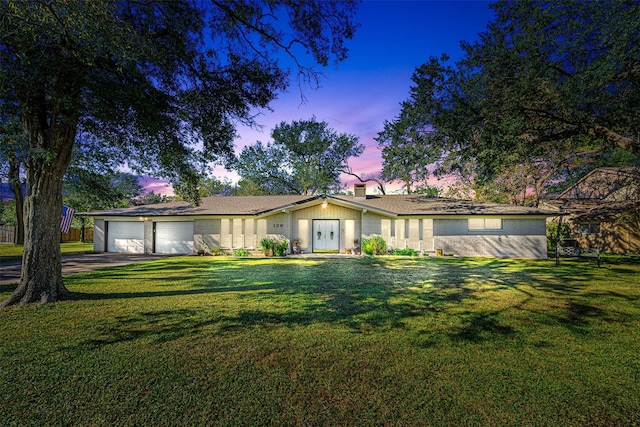 single story home featuring a lawn and a garage