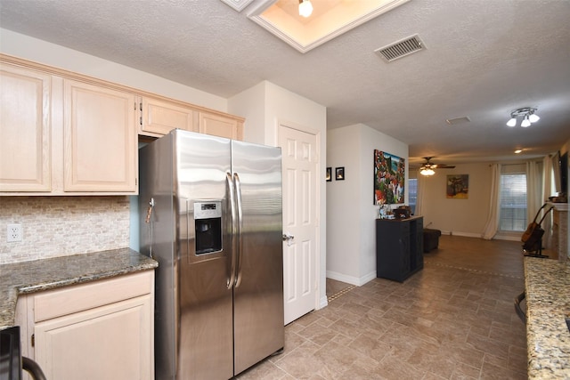 kitchen with stainless steel refrigerator with ice dispenser, backsplash, a textured ceiling, ceiling fan, and dark stone countertops