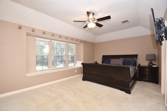 carpeted bedroom with a raised ceiling and ceiling fan