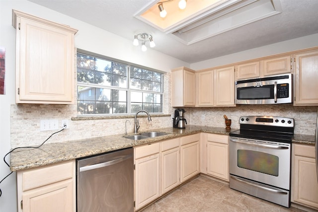 kitchen with decorative backsplash, appliances with stainless steel finishes, light stone counters, and sink