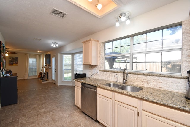 kitchen featuring dishwasher, ceiling fan, light stone counters, and sink