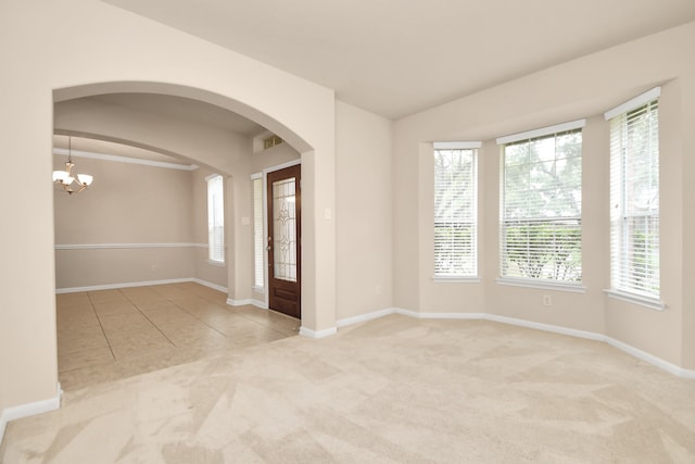 unfurnished room featuring light carpet, a wealth of natural light, and a chandelier