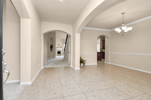 foyer entrance featuring crown molding, light tile patterned floors, and an inviting chandelier