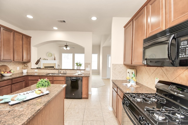 kitchen featuring light stone countertops, sink, tasteful backsplash, light tile patterned floors, and black appliances