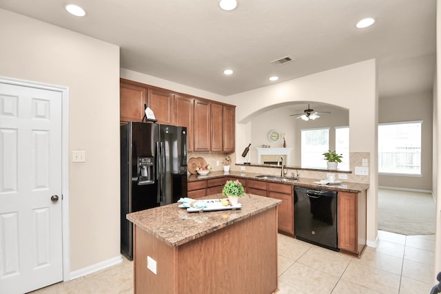 kitchen featuring black appliances, sink, light stone countertops, a kitchen island, and kitchen peninsula