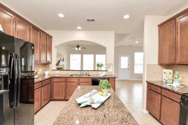 kitchen featuring stone counters, a healthy amount of sunlight, and black appliances