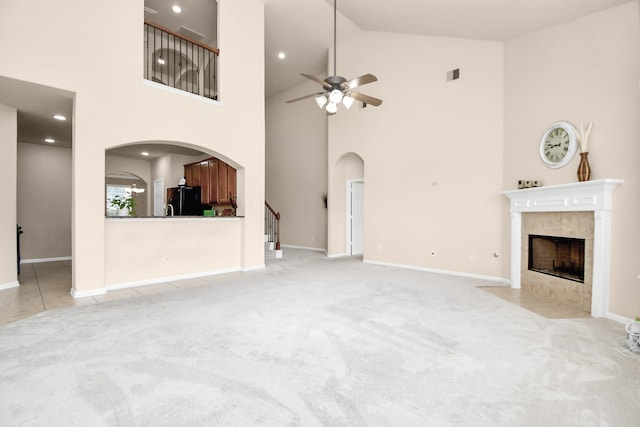 unfurnished living room featuring light carpet, a fireplace, high vaulted ceiling, and ceiling fan