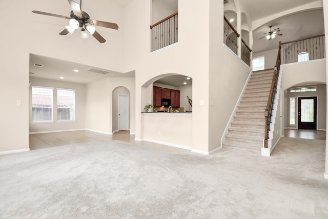 unfurnished living room featuring light colored carpet, a towering ceiling, and french doors