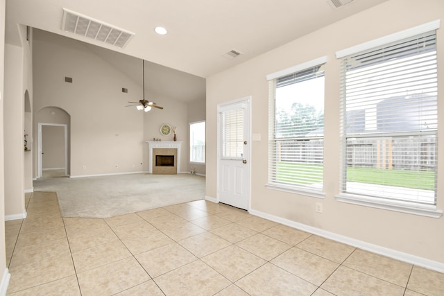 interior space with a tile fireplace, light tile patterned floors, high vaulted ceiling, and ceiling fan