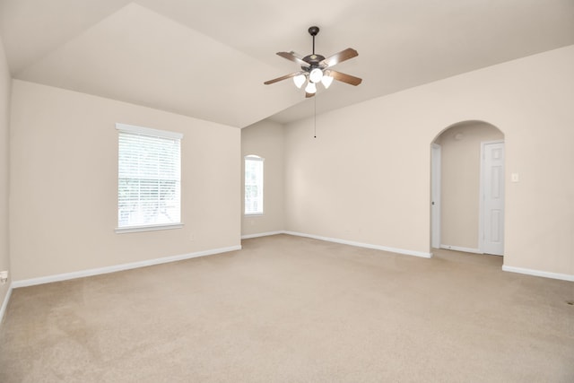 empty room featuring light carpet, ceiling fan, and vaulted ceiling