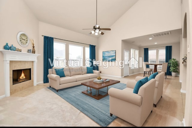 living room featuring a tile fireplace, plenty of natural light, high vaulted ceiling, and light hardwood / wood-style floors