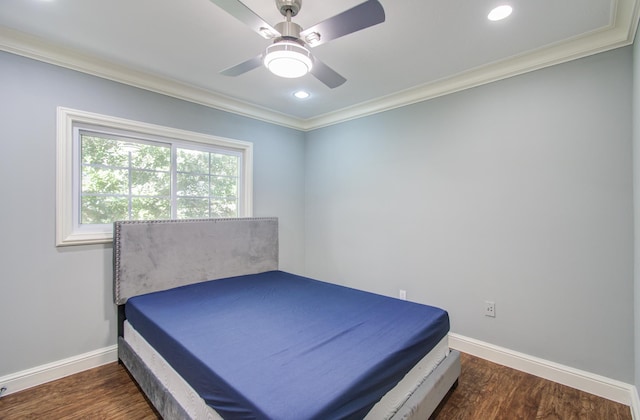 bedroom featuring dark hardwood / wood-style floors, ceiling fan, and crown molding