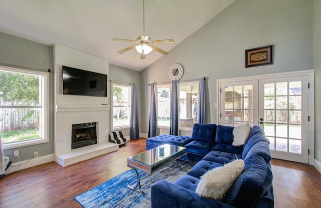 living room featuring high vaulted ceiling, french doors, hardwood / wood-style flooring, ceiling fan, and a fireplace