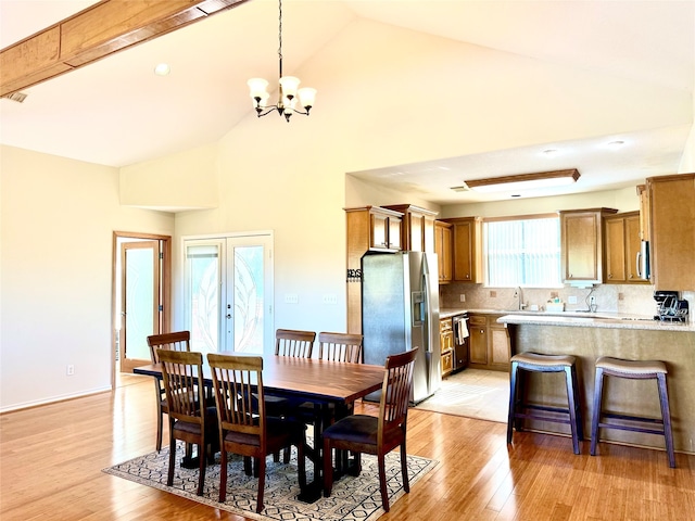 dining room with high vaulted ceiling, french doors, sink, light hardwood / wood-style floors, and a chandelier