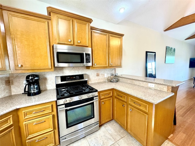 kitchen featuring kitchen peninsula, appliances with stainless steel finishes, tasteful backsplash, light stone counters, and light hardwood / wood-style flooring