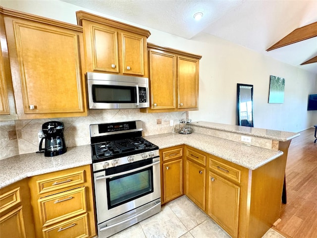 113 Cottonwood Rd, Trinity, TX 75862 - kitchen featuring appliances with stainless steel finishes, a peninsula, decorative backsplash, brown cabinets, and light stone counters