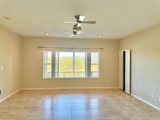 unfurnished room with ceiling fan, light tile patterned floors, and a textured ceiling