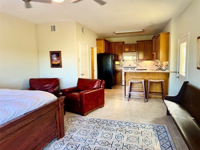 tiled bedroom with ceiling fan and black refrigerator