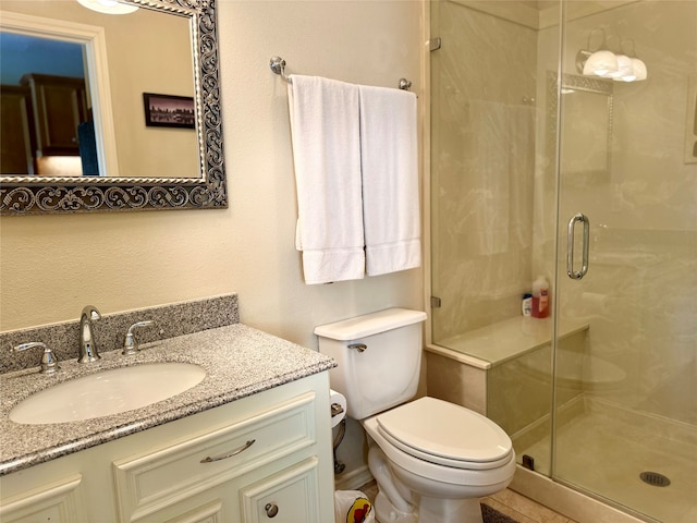 bathroom with a shower with door, vanity, and toilet