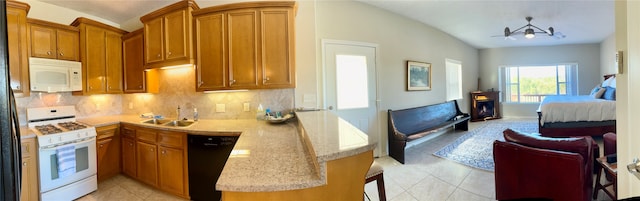 kitchen with kitchen peninsula, decorative backsplash, white appliances, an inviting chandelier, and a breakfast bar area