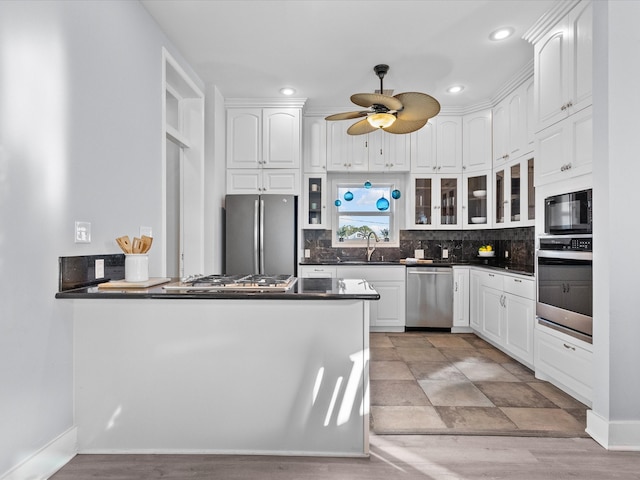 kitchen with kitchen peninsula, sink, white cabinets, and appliances with stainless steel finishes