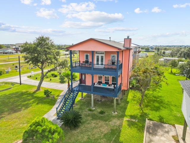 rear view of house with a yard and a balcony