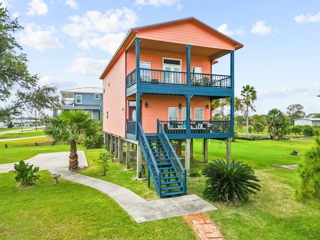 back of house with covered porch, a balcony, and a lawn