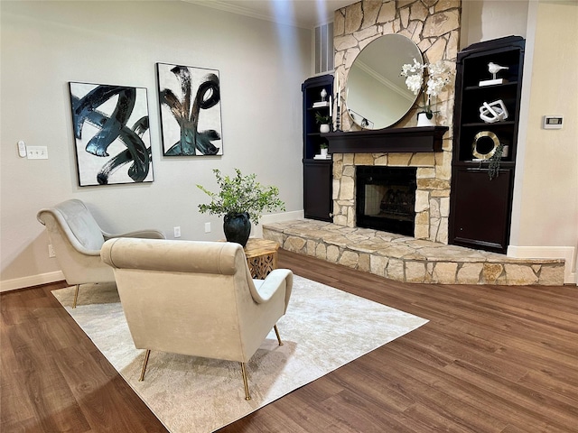 living room with hardwood / wood-style floors, a stone fireplace, and crown molding