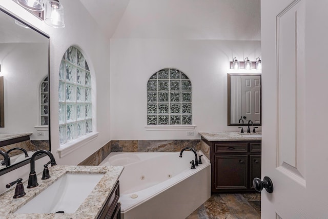 bathroom with a washtub, vanity, and lofted ceiling