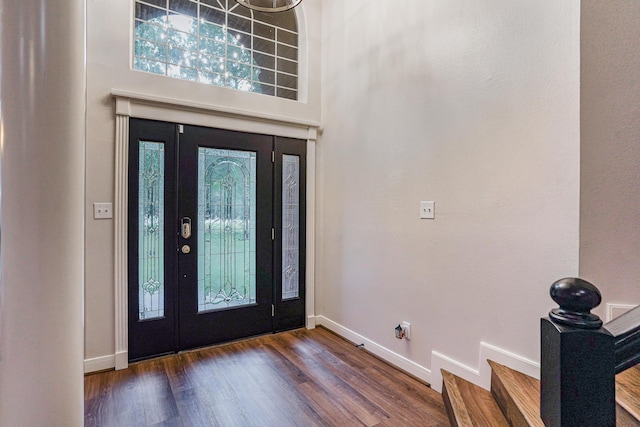 entryway with a towering ceiling and dark wood-type flooring