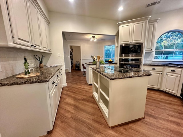 kitchen with white cabinets, a kitchen island, stainless steel appliances, and light hardwood / wood-style flooring