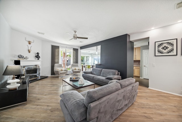 living room featuring a textured ceiling, light wood-type flooring, and ceiling fan