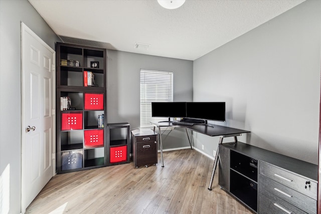 office with light hardwood / wood-style floors and a textured ceiling