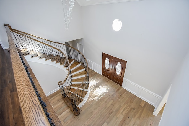 foyer entrance featuring hardwood / wood-style floors, crown molding, and a high ceiling