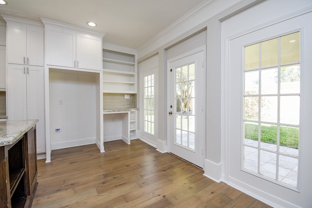 doorway with ornamental molding and light wood-type flooring