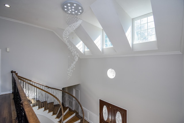 stairway featuring a notable chandelier, wood-type flooring, and crown molding