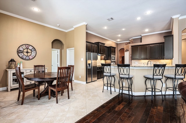 dining area with sink, crown molding, and light hardwood / wood-style flooring