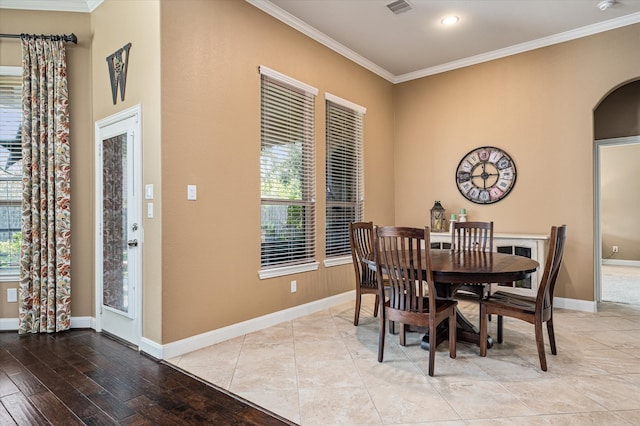 dining space with ornamental molding and light wood-type flooring