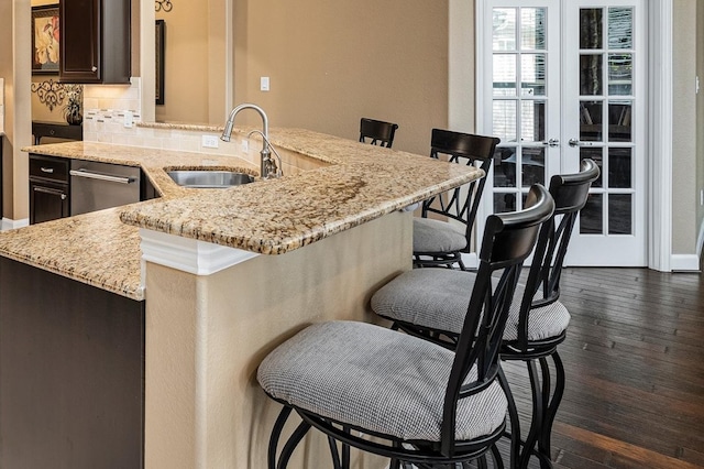 kitchen with a kitchen bar, tasteful backsplash, dark brown cabinets, sink, and dark hardwood / wood-style floors