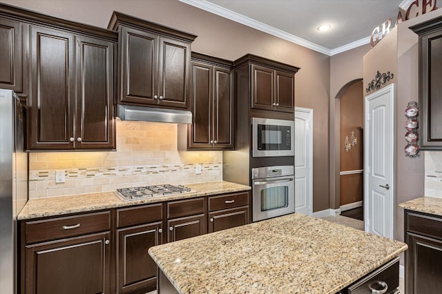 kitchen with dark brown cabinetry, light stone counters, decorative backsplash, appliances with stainless steel finishes, and ornamental molding