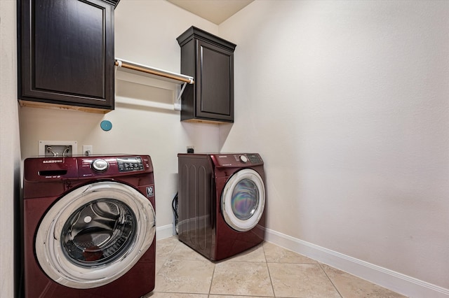 washroom featuring cabinets, light tile patterned floors, and washing machine and clothes dryer